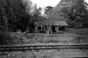 black and white shot of a dilapidated building by a railway track