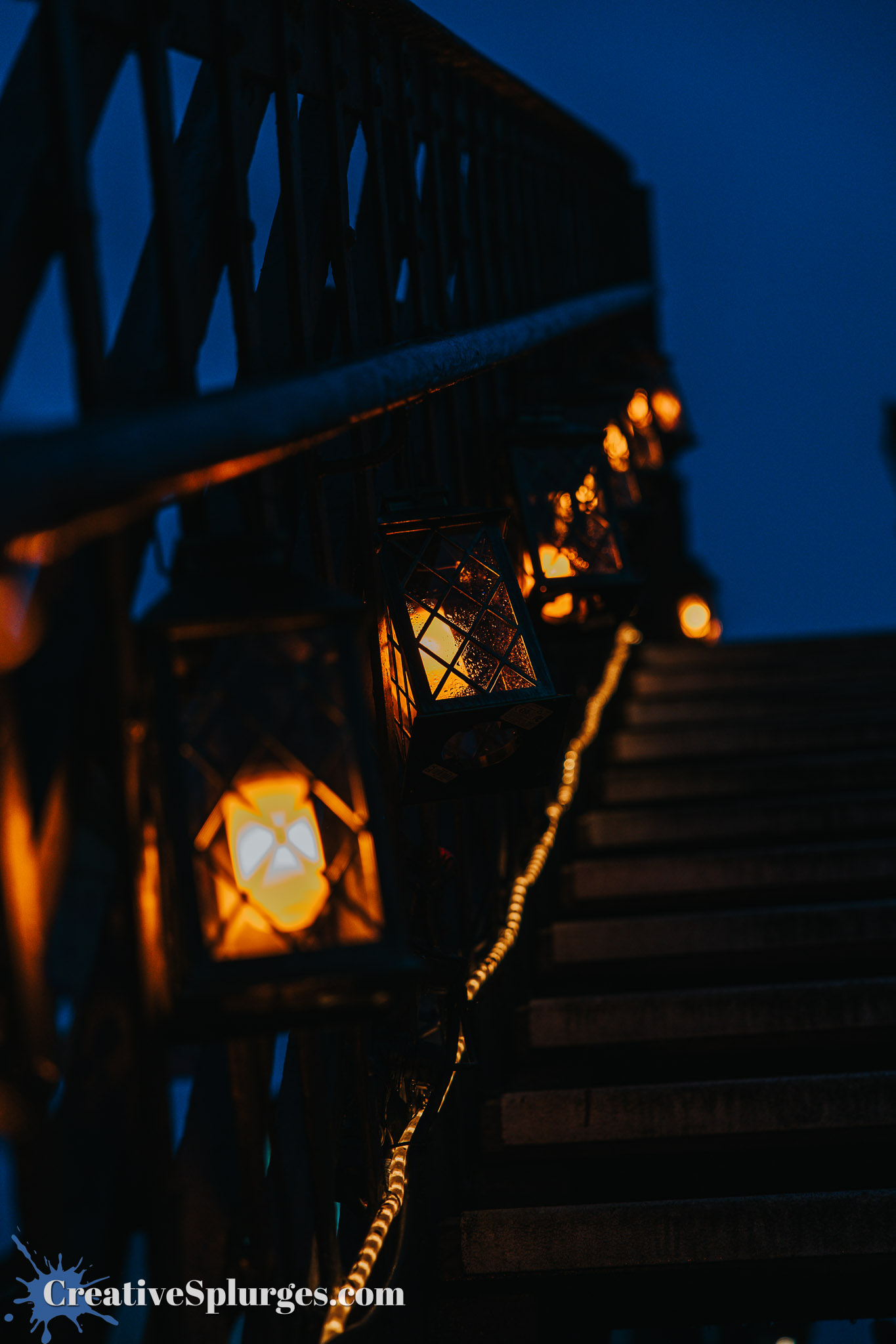 A close-up view of a staircase illuminated by decorative lanterns, set against a twilight sky.