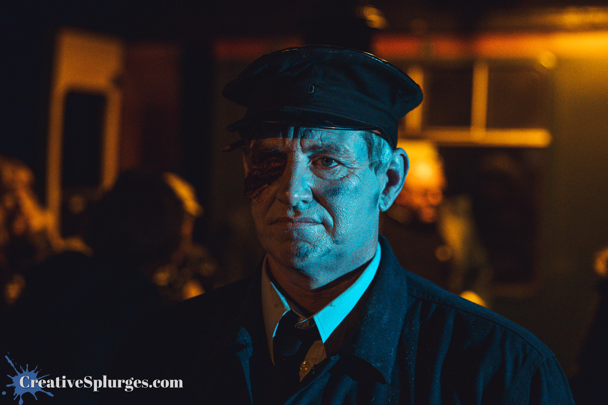 A man wearing a dark uniform and cap, with a heavily scarred and bruised face, appearing serious against a dimly lit background.